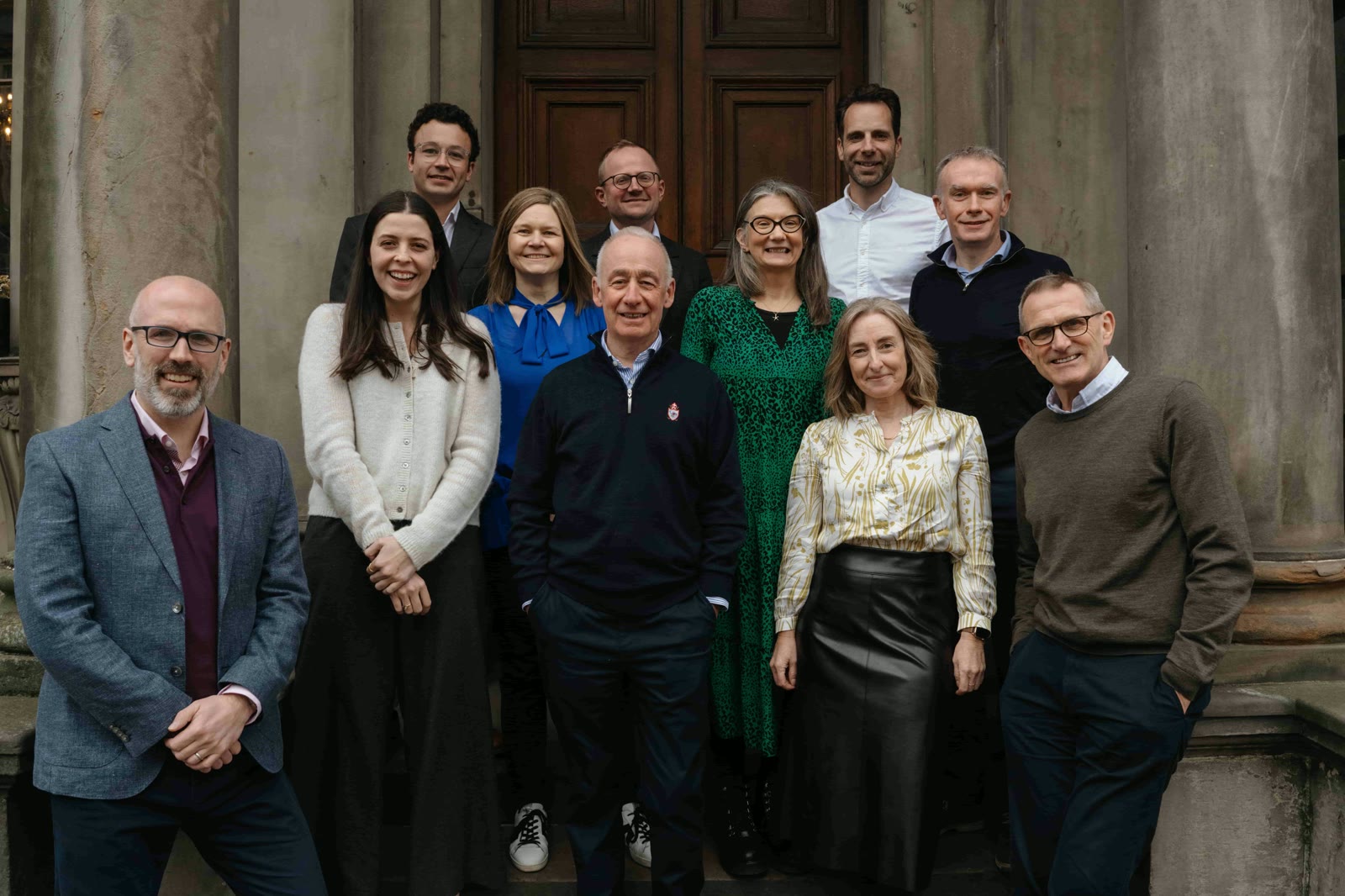The Eos team on the steps of a stone building in St Andrews
